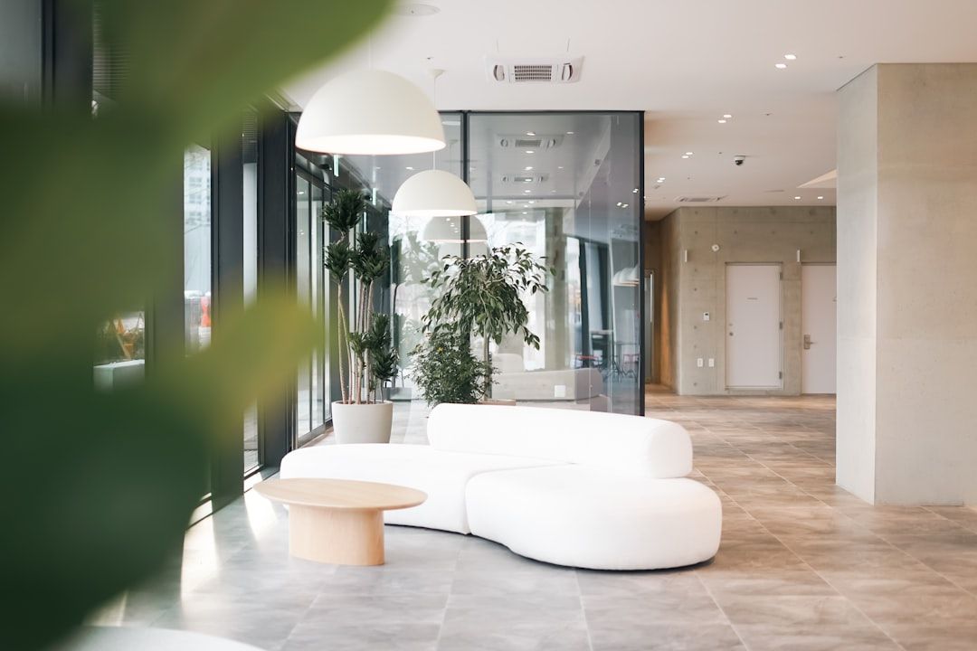 Modernt loungeområde i ett kontorshotell med en vit soffa och gröna växter.