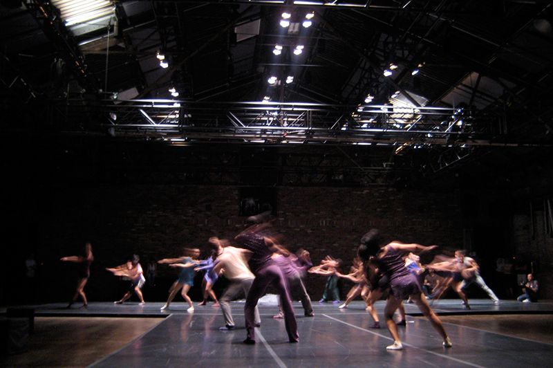 Dansare och skådespelare under en fartfylld repetition på en teaterscen.